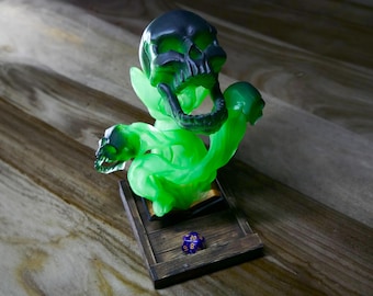 May include: A green and black skull dice tower with a swirling, smoke-like design. The tower is made of resin and has a wooden base with a single purple and orange dice on top.