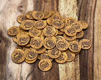 May include: A pile of gold-coloured metal coins with intricate designs on a wooden surface.