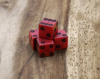 May include: Four red dice with black dots are arranged on a wooden surface. The dice are a bright red, and the dots are black. The wooden surface has a natural wood grain pattern, adding a rustic feel.
