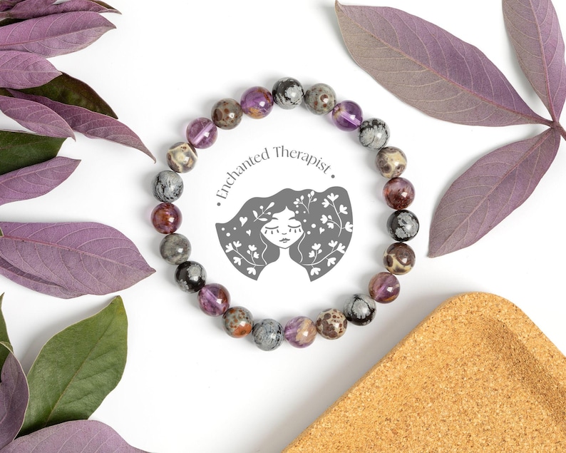 May include: A purple, grey, and black gemstone bracelet with a logo that says "Enchanted Therapist".