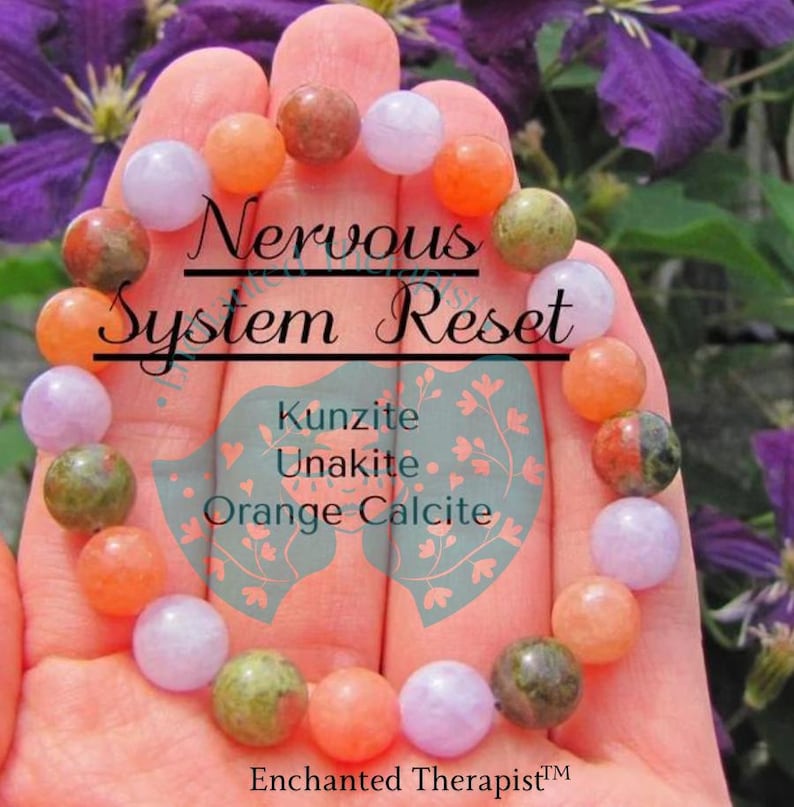 May include: A bracelet made with pink, green, and orange stones. The bracelet is labeled "Nervous System Reset" and lists the stones as Kunzite, Unakite, and Orange Calcite. The bracelet is held in a hand against a background of purple flowers.