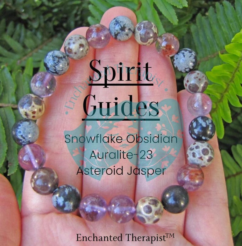 May include: A bracelet made with snowflake obsidian, Auralite-23, and asteroid jasper beads. The bracelet is on a hand and has the text "Spirit Guides" on it.