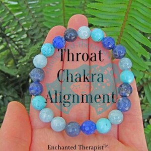 May include: A blue and turquoise gemstone bracelet with the text "Throat Chakra Alignment" on a hand.
