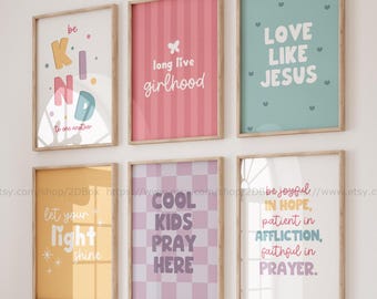 May include: A collection of six framed art prints with inspirational quotes. The prints feature various colors and designs, including the phrases "be KIND," "long live girlhood," and "LOVE LIKE JESUS." The prints are displayed above a bench with pillows.