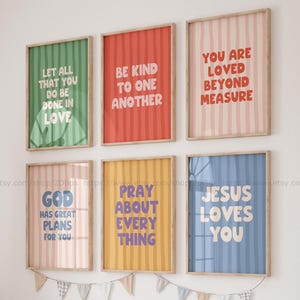 May include: Six framed art prints with positive affirmations. Each print has a different coloured background with vertical stripes and a bold, sans-serif font. The quotes include "Be kind to one another" and "Jesus loves you."
