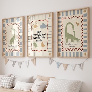 Peut inclure: Trois impressions d'art encadrées avec des citations inspirantes et des illustrations de dinosaures. Les impressions présentent un fond rayé bleu clair et blanc avec une bordure décorative. L'œuvre comprend un dinosaure, le soleil, la lune et une feuille. Le texte dit : "Je suis fort et courageux", "Je suis fait de façon merveilleuse", et "Je suis aimé au-delà de toute mesure."