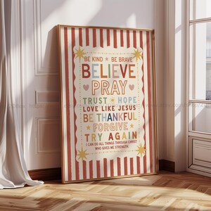May include: A framed vertical wall art print featuring a cream background with red vertical stripes. The text reads: BE KIND, BE BRAVE, BELIEVE, PRAY, TRUST, HOPE, LOVE LIKE JESUS, BE THANKFUL, FORGIVE, TRY AGAIN, I CAN DO ALL THINGS THROUGH CHRIST.
