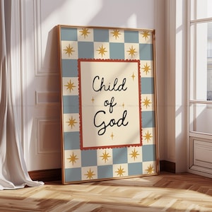 Puede incluir: Impresión artística enmarcada con las palabras "Child of God" en escritura negra sobre un fondo crema. La impresión está enmarcada en dorado y colocada sobre un patrón de cuadros azules y crema con acentos de estrellas doradas. El marco está apoyado contra una pared blanca.