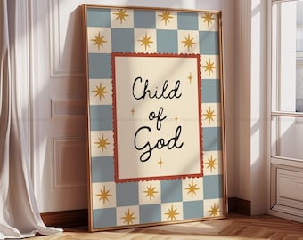 May include: Framed art print with the words "Child of God" in black script on a cream background. The print is framed in gold and set against a blue and cream checkered pattern with gold star accents. The frame is leaning against a white wall.