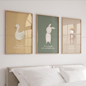 May include: Three framed art prints with cartoon animals: a duck, a rabbit, and a monkey. Each print has a different background colour and a motivational quote. The duck is on a yellow background, the rabbit on a green background, and the monkey on a tan background.