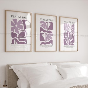 May include: Three framed wall art prints featuring abstract purple floral illustrations on a white background. Each print displays a specific Bible verse: Psalm 89:1, Psalm 28:7, and Psalm 9:1, with corresponding text printed in black below each floral design.