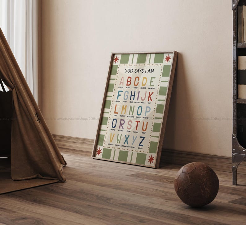 May include: A framed alphabet chart with the text "GOD SAYS I AM" and colorful letters. The chart has a green and white checkered background and is leaning against a wall. A brown soccer ball rests on the wooden floor.