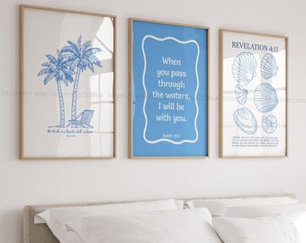 May include: Three framed prints with a blue background. The left print features a drawing of two palm trees and a beach chair with the text "He leads me beside still waters." The middle print features the text "When you pass through the waters, I will be with you."  Isaiah 43:2. The right print features a drawing of seashells with the text "Revelation 4:11".