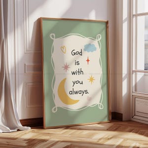 Könnte beinhalten: Gerahmter Kunstdruck mit goldenem Rahmen. Das Kunstwerk zeigt den Text "Gott ist immer bei dir" mit Illustrationen von Herz, Wolke, Sternen und einem Mond auf hellgrünem Hintergrund.