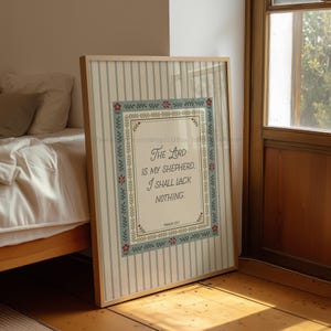 May include: Framed print with the text "The Lord is my Shepherd. I shall lack nothing." The print has a light blue and white striped background with a decorative border and floral accents. The frame is a light wood color.