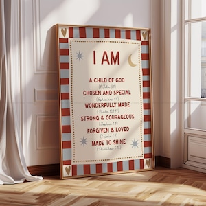 May include: Framed wall art with a cream-colored background and the words "I AM" in large letters. The text below lists affirmations such as "A Child of God" and "Chosen and Special." The frame has a gold finish with red and gray stripes.