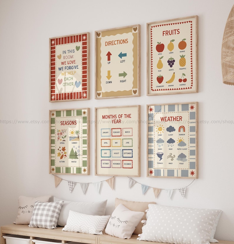 May include: A collection of framed educational posters with colorful designs. The posters display words like "Directions", "Fruits", "Seasons", "Months of the Year", and "Weather". The frames are beige with decorative borders, and the posters are hung on a white wall.