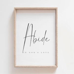 Puede incluir: Una impresión enmarcada con la palabra "Abide" en una fuente cursiva y el texto "in God's love" debajo.