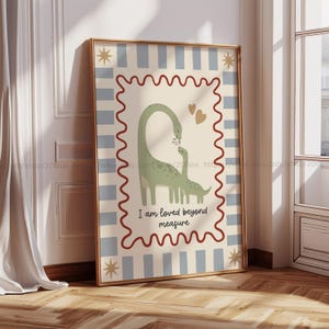 Könnte beinhalten: Ein gerahmter Kunstdruck mit einem hellgrünen Dinosaurier-Elternteil und -Kind mit einer Blume. Der Hintergrund ist cremefarben mit blauen Streifen und goldenen Sternen. Der Text "I am loved beyond measure" steht unten.