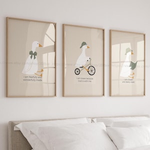 Puede incluir: Tres impresiones enmarcadas con gansos de dibujos animados en varias poses. Un ganso lleva un lazo, otro monta en bicicleta y el tercero lee un libro. Cada impresión tiene una cita inspiradora diferente. Los marcos son de color marrón claro.