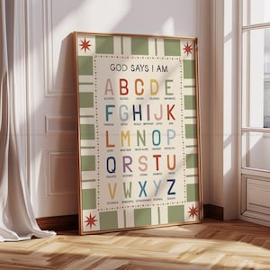 May include: A framed poster with the text "GOD SAYS I AM" and an alphabet with positive affirmations. The poster has a beige background with green stripes and a gold frame. The letters are in various colors.