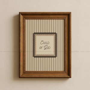 May include: A framed print with the words "Child of God" in elegant script. The artwork features a striped background in neutral tones, a decorative border, and a dark brown wooden frame. A piece of inspirational wall art.