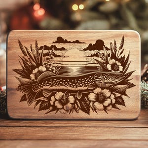 May include: A rectangular wooden cutting board with a detailed engraved design. The design features a fish, flowers, and foliage, set against a backdrop of a lake and sky. The board is made of light-colored wood.