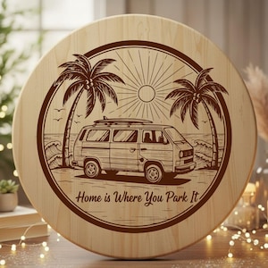 May include: Circular wooden sign with a beach scene etched in brown. The design features a van with a surfboard, palm trees, waves, and the sun. The text "Home is Where You Park It" is also included.