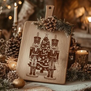 A wooden cutting board with a nutcracker illustration and a Christmas tree design, surrounded by pine cones, candles, and other holiday decorations.
