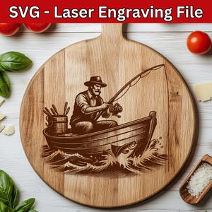 Puede incluir: Una tabla de cortar redonda de madera con un asa, con una ilustración grabada con láser de un pescador en un barco. El pescador sostiene una caña de pescar, con un pez saltando fuera del agua. El texto "SVG - Laser Engraving File" está en la parte superior.