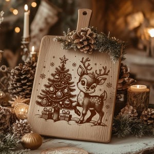 May include: Wooden cutting board with a handle, featuring a Christmas tree and a deer illustration. The board is decorated with pine cones and greenery. The design is etched in brown on the light-colored wood. The board is surrounded by candles and ornaments.