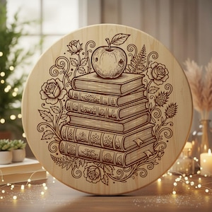 Può includere: Un elemento decorativo rotondo in legno con un design inciso. Il design presenta una pila di libri sormontata da una mela, circondata da rose e foglie. Il pezzo è di colore marrone chiaro.