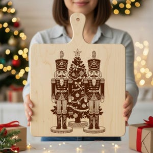 A woman is holding a wooden cutting board with a nutcracker and Christmas tree design on it.
