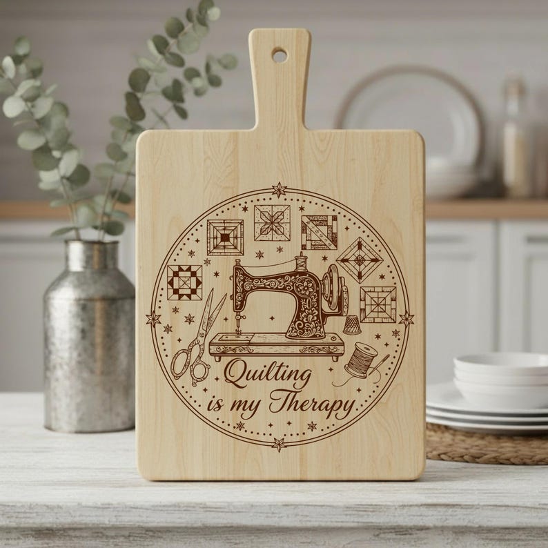 May include: Wooden chopping board with a handle, featuring a decorative design. The design includes a vintage sewing machine, scissors, and the text "Quilting is my Therapy." Various quilt block patterns surround the sewing machine. The board is made of light-coloured wood.