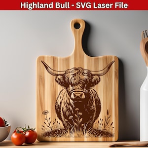 Puede incluir: Una tabla de cortar de madera con un diseño grabado con láser de un toro de las Tierras Altas de Escocia de pie en un campo de hierba. El toro es marrón y tiene pelo largo y peludo. La tabla de cortar es rectangular y tiene un asa en la parte superior.