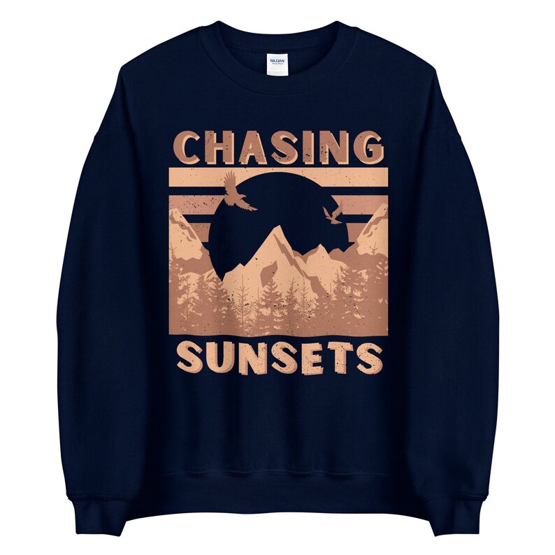May include: Navy blue sweatshirt with a brown graphic of mountains, a sunset, and birds flying. The text "CHASING SUNSETS" is printed in brown on the sweatshirt.