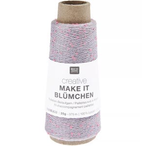 Könnte beinhalten: Eine Spule graues Garn mit rosa Tupfen, beschriftet mit "creative MAKE IT BLÜMCHEN". Das Etikett gibt außerdem an, dass das Garn 25g-375m und 100% Lyocell ist. Das Garn ist um einen Pappkern gewickelt, geeignet zum Stricken und für andere Handarbeiten.