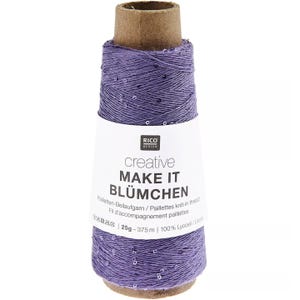 Könnte beinhalten: Eine Spule lavendelfarbenes Garn mit eingebetteten Pailletten. Das Garn ist um eine Papprolle gewickelt. Ein weißes Etikett mit dem Text "creative MAKE IT BLÜMCHEN" ist um die Spule gewickelt. Das Etikett enthält auch den Text "25g - 375 m".