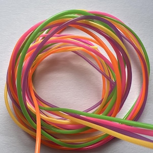 Könnte beinhalten: Ein Bündel bunter Neon-grüner, gelber, orangefarbener, rosa und violetter Kunststoffschnüre. Die Schnüre sind zu einem Kreis verdreht.