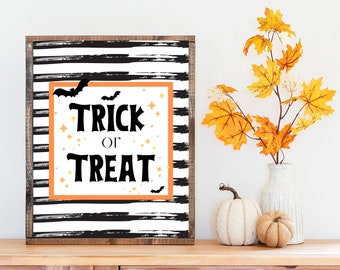 Puede incluir: Un cartel de rayas blancas y negras con marco de madera. El cartel tiene las palabras "Trick or Treat" en letras negras con estrellas y murciélagos naranjas.