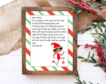 May include: A letter from Arlo the Elf to Ethan, with red and green striped paper and a cartoon elf illustration. The letter reads, "Dear Ethan, I've missed you this year but I'm back to play! I'll be staying again until Christmas Day. I'm looking forward to reporting to Santa each night, as I know there will only be kindness and love within sight. Don't forget not to touch me or my magic I'll lose. And I'll try not to get into too much trouble while you snooze. Love, Arlo the Elf"