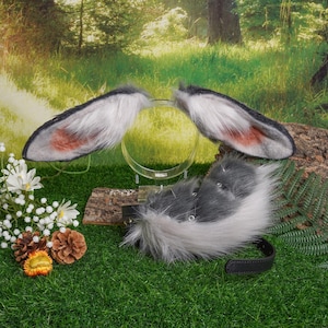 Può includere: Una coda pelosa grigia e bianca con un cerchietto nero e un cerchietto peloso grigio e bianco abbinato con orecchie.