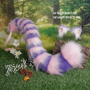 May include: A plush, striped tail in shades of pink and purple, with matching ear accessories. The tail measures 35.43 inches long. The ear height is 3.15 inches. The accessories are displayed on a grassy surface with flowers and pinecones.
