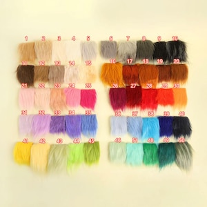 Op de afbeelding: Een verzameling van 50 stalen van imitatiebont in verschillende kleuren, gerangschikt in rijen. De kleuren variëren van lichte neutralen tot levendige tinten, waaronder roze, blauw, groen en oranje. Elk staal is genummerd.