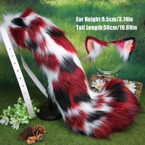 May include: A fluffy faux fur tail and ear set in red, black, and white. The tail is 50cm long and has a white strap. The ears are on a clear headband. The text on the image says: Ear Height: 9.5cm, Tail Length: 50cm.