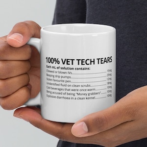 May include: A white ceramic mug with a black design that reads "100% Vet Tech Tears" and lists the ingredients of "each mL of solution contains:" including "Chewed or blown IVs", "Beeping drip pumps", "Stolen favourite pen", "Unidentified fluid on clean scrubs", "Cold beverages that were once warm", "Being accused of being "Money grabbers", and "Explosive diarrhoea in a clean kennel".