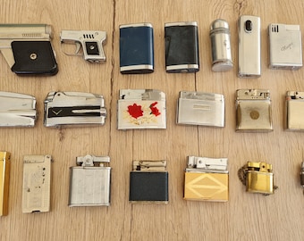May include: A collection of vintage lighters, including a gun-shaped lighter, a lighter with a floral design, and a lighter with a gold finish.