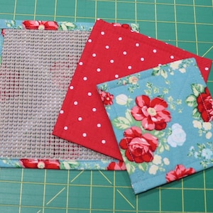 May include: Three fabric squares, one with a beige mesh center, one with red polka dots on a red background, and one with a floral pattern on a blue background.