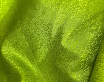 May include: Vibrant lime green fabric with a delicate floral design. The material has a slight sheen, and the folds create shadows that accentuate the texture. The overall appearance is luxurious, ideal for clothing or interior design projects.