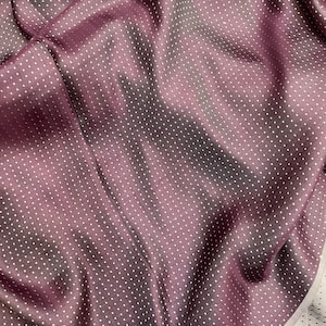 May include: A close-up of a purple fabric with a white polka dot pattern. The fabric is soft and has a subtle sheen.